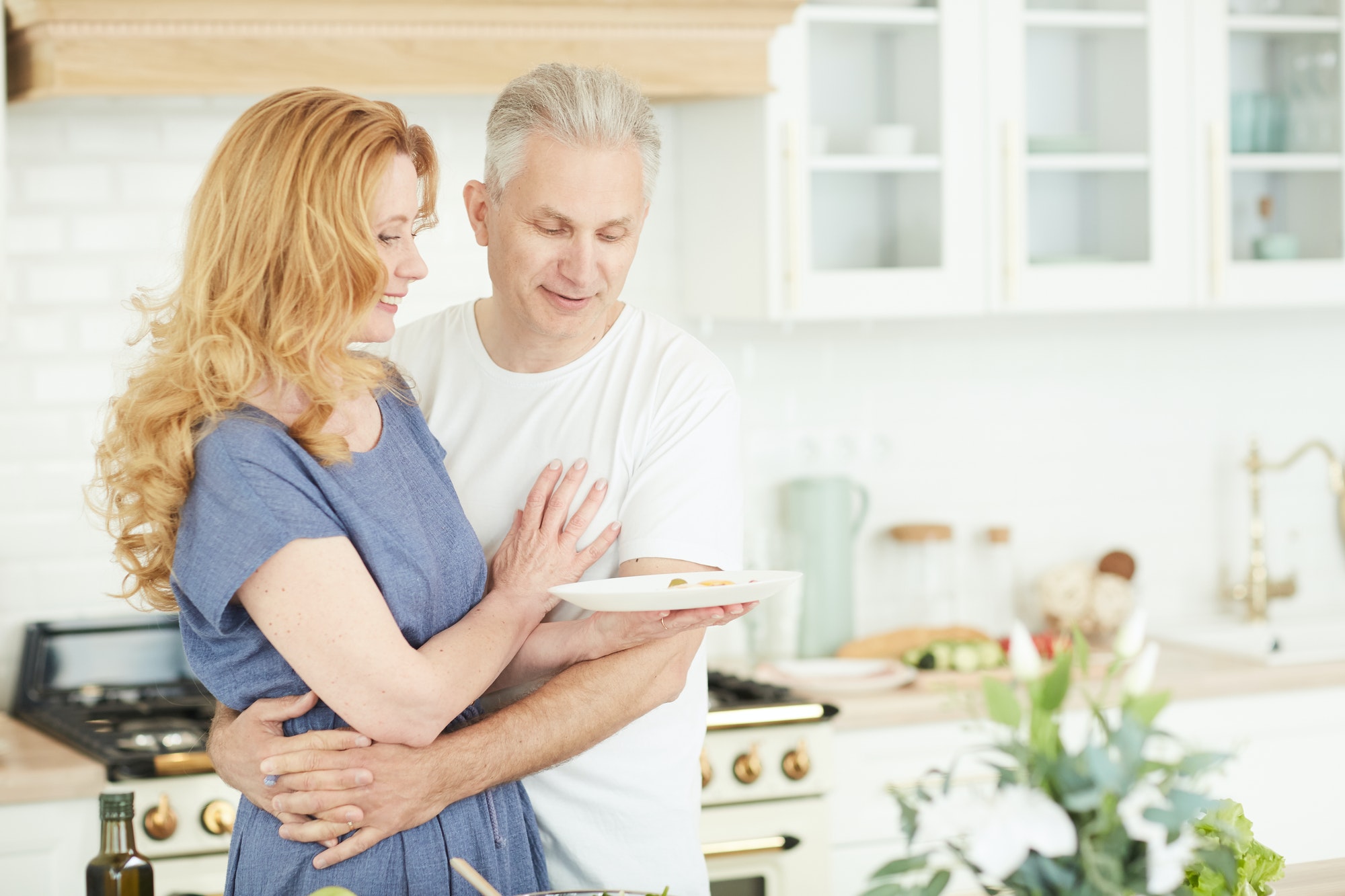 Imagem de casal de meia idade se relacionando de forma saudável na cozinha. A imagem ilustra a chamada para o Blog escrito pelo Psicanalista Homero Mônaco para o site Online Psicanalista.